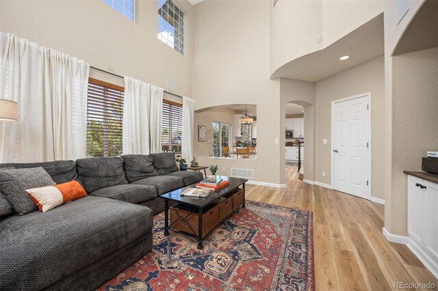 4467 Trailside Ln, Castle Rock, CO 80109 - living room with arched walkways, a high ceiling, light wood-style floors, and baseboards