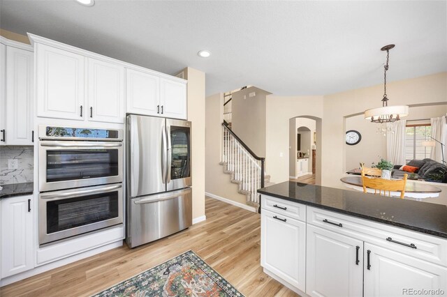 4467 Trailside Ln, Castle Rock, CO 80109 - kitchen with stainless steel appliances, arched walkways, a chandelier, white cabinets, and recessed lighting