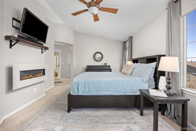 4467 Trailside Ln, Castle Rock, CO 80109 - carpeted bedroom featuring lofted ceiling, baseboards, a glass covered fireplace, a ceiling fan, and arched walkways