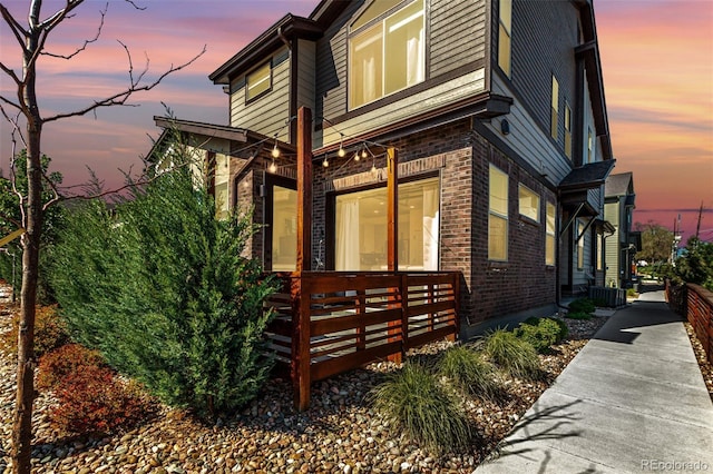 view of side of home featuring central AC and brick siding
