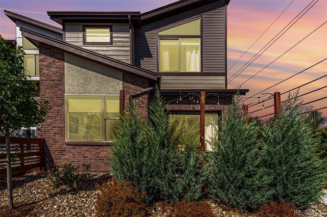 property exterior at dusk featuring brick siding