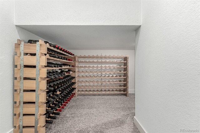 wine area featuring a textured wall, carpet flooring, and baseboards
