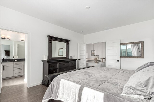 bedroom featuring wood finished floors, baseboards, and ensuite bath