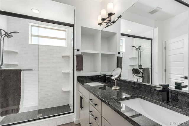 bathroom featuring a shower stall, double vanity, and recessed lighting