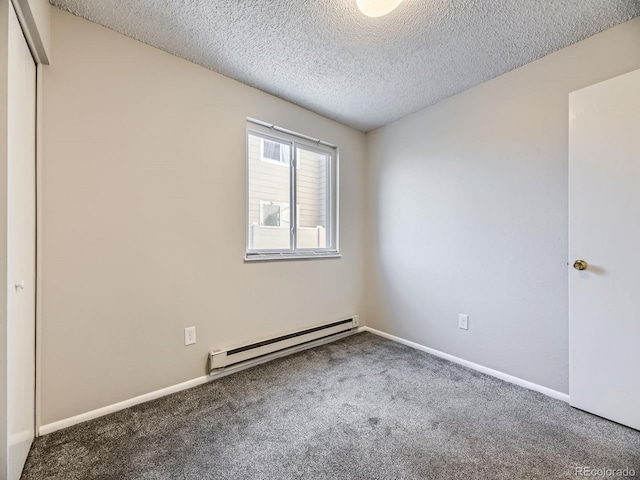 empty room featuring a textured ceiling, carpet floors, and a baseboard heating unit