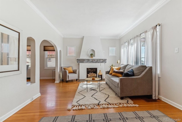 living room with a wealth of natural light, crown molding, and a fireplace