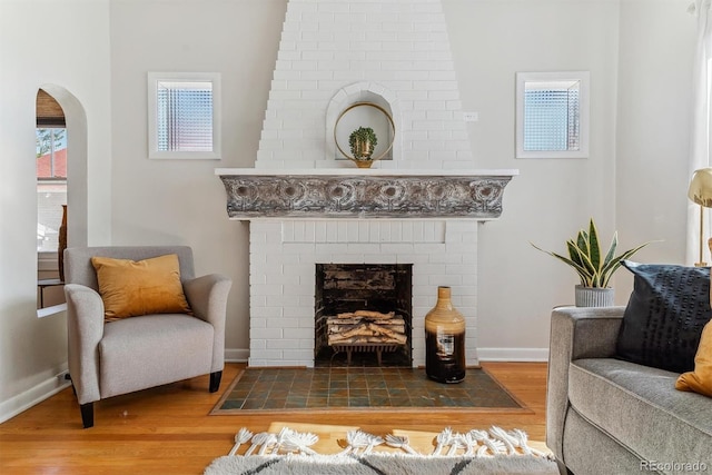 living area featuring a brick fireplace and hardwood / wood-style flooring