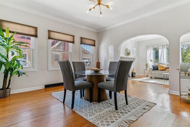 dining room with light wood-type flooring, an inviting chandelier, and ornamental molding