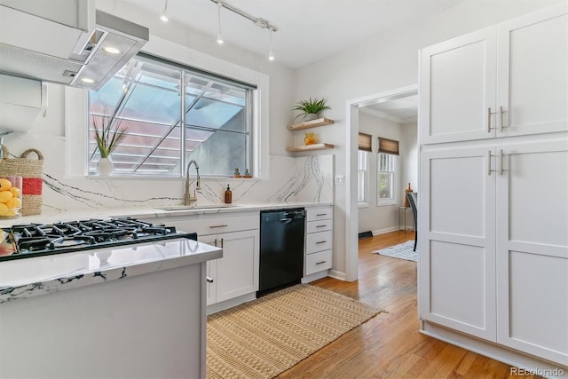 kitchen with white cabinets, dishwasher, tasteful backsplash, sink, and light hardwood / wood-style flooring