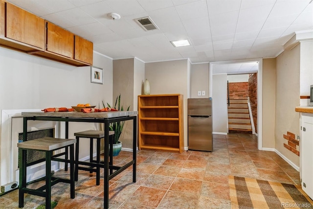 kitchen with stainless steel fridge, ornamental molding, and a breakfast bar area