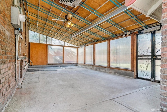 interior space with ceiling fan, brick wall, and lofted ceiling