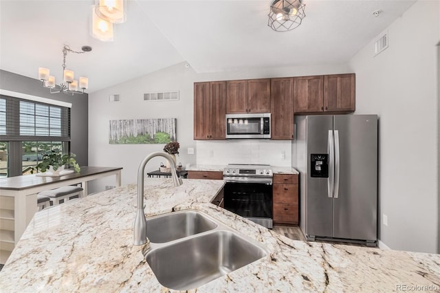 2955 Blue Sky Cir Unit 6-307, Erie, CO 80516 - kitchen featuring stainless steel appliances, a chandelier, lofted ceiling, backsplash, and light stone countertops