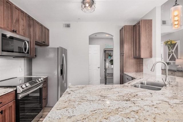 2955 Blue Sky Cir Unit 6-307, Erie, CO 80516 - kitchen with stainless steel appliances, decorative backsplash, arched walkways, and light stone countertops