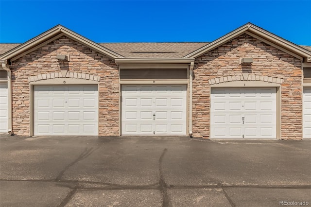 2955 Blue Sky Cir Unit 6-307, Erie, CO 80516 - view of front facade with community garages, a shingled roof, and stone siding