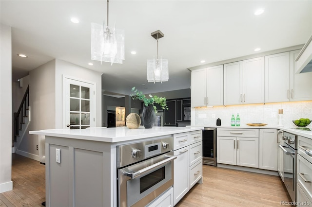 kitchen featuring a center island, light countertops, backsplash, light wood-style floors, and oven