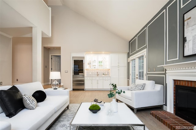 living room with light wood finished floors, a fireplace, high vaulted ceiling, and french doors