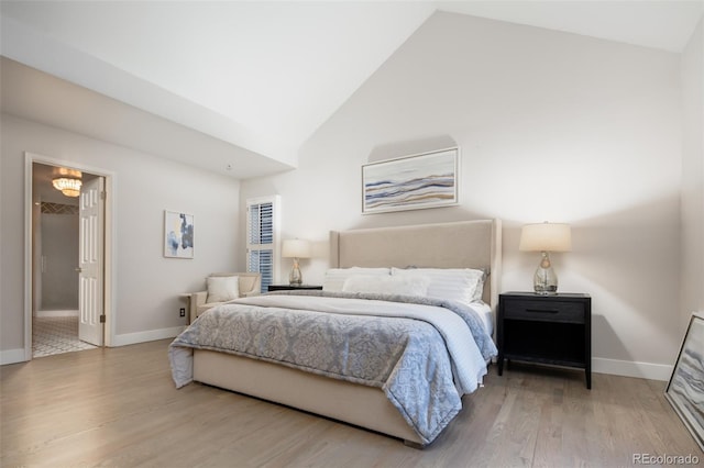 bedroom with high vaulted ceiling, baseboards, and wood finished floors