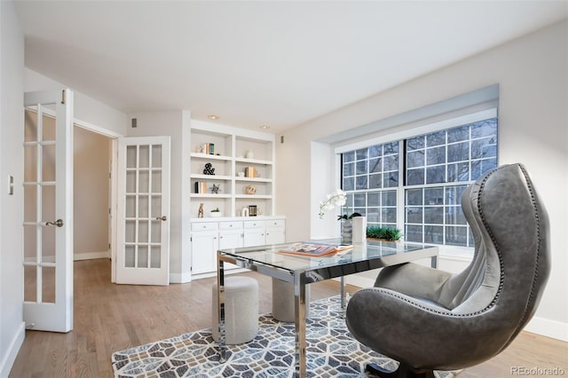 office area featuring built in shelves, baseboards, wood finished floors, and french doors