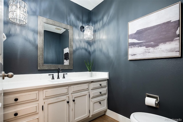 half bath with toilet, vanity, and baseboards