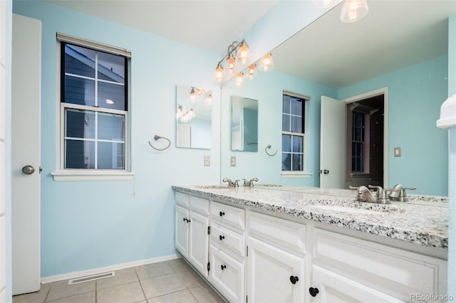 bathroom with double vanity, baseboards, visible vents, tile patterned floors, and a sink