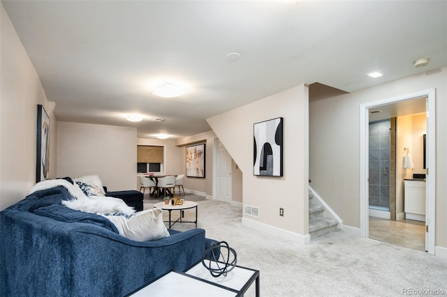 carpeted living area with stairs, visible vents, and baseboards