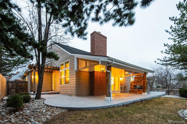 rear view of property with a chimney, a patio area, and fence