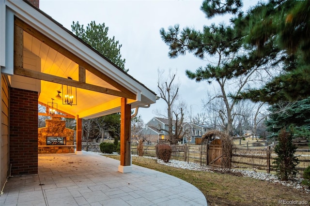 view of patio / terrace with an outdoor stone fireplace and fence