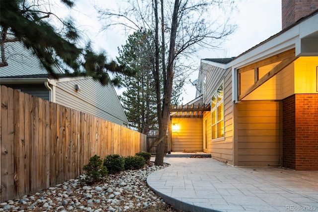 view of property exterior featuring a patio, fence, and a pergola