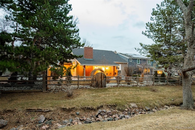 back of house with a fenced front yard and a chimney