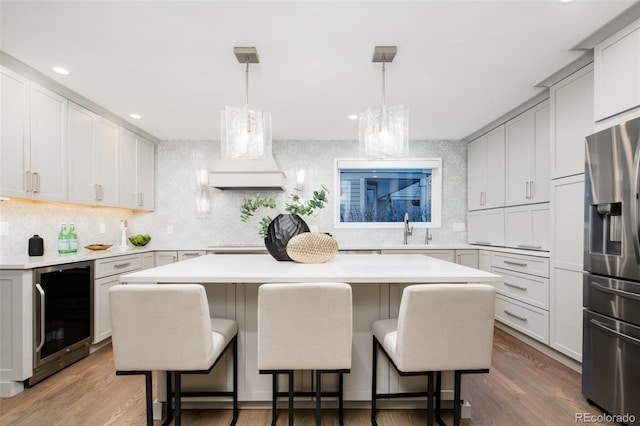 kitchen featuring a center island, wine cooler, stainless steel fridge, backsplash, and light countertops