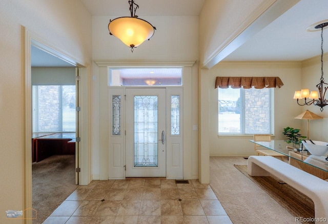 carpeted entryway with an inviting chandelier and ornamental molding