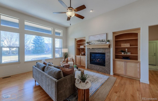 living room with ceiling fan, a fireplace, and light wood-type flooring