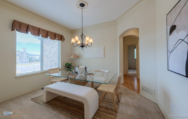 dining room featuring crown molding, carpet, and a chandelier