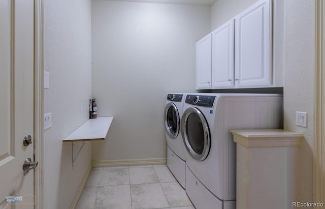 laundry area featuring light tile patterned flooring, cabinets, and washer and dryer