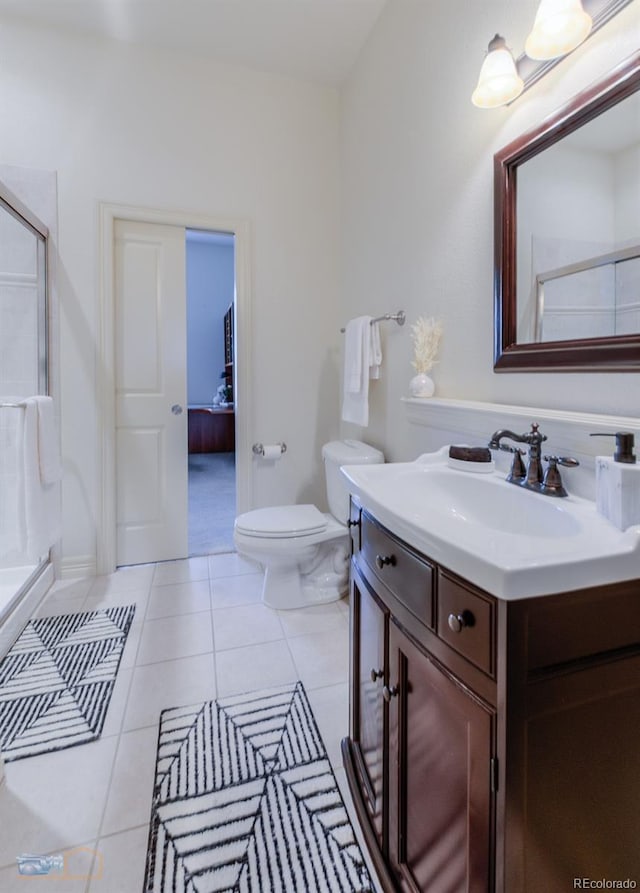 bathroom featuring tile patterned floors, toilet, a shower with door, and vanity