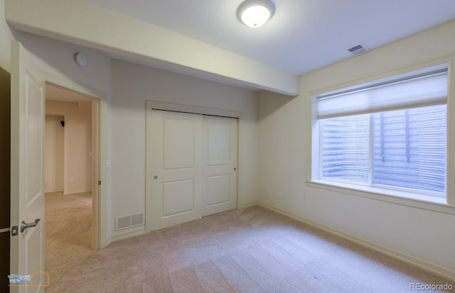 unfurnished bedroom featuring a closet and light carpet