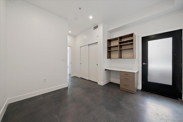 unfurnished bedroom featuring built in desk and a closet