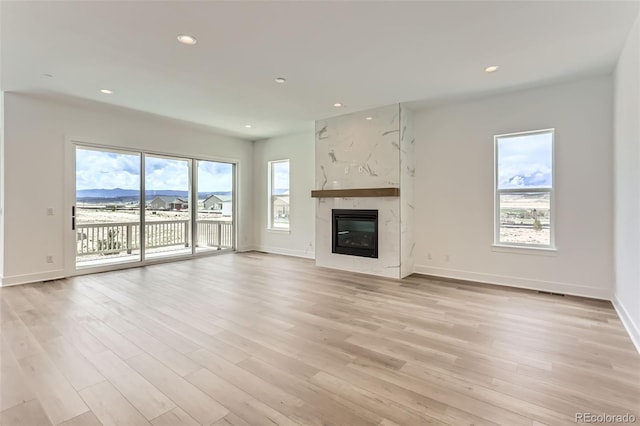 unfurnished living room with light wood-type flooring, baseboards, and recessed lighting
