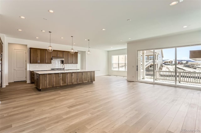 kitchen with open floor plan, light wood finished floors, decorative backsplash, under cabinet range hood, and recessed lighting