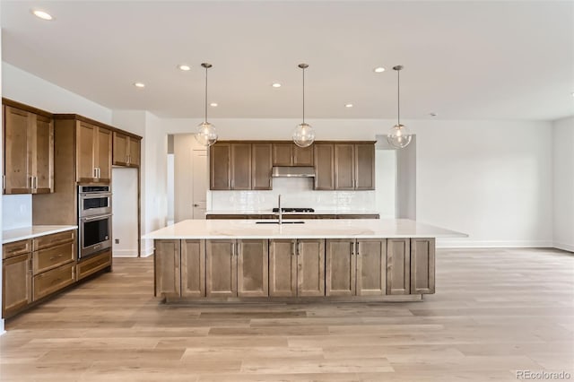 kitchen featuring double oven, decorative backsplash, light countertops, light wood-style flooring, and recessed lighting