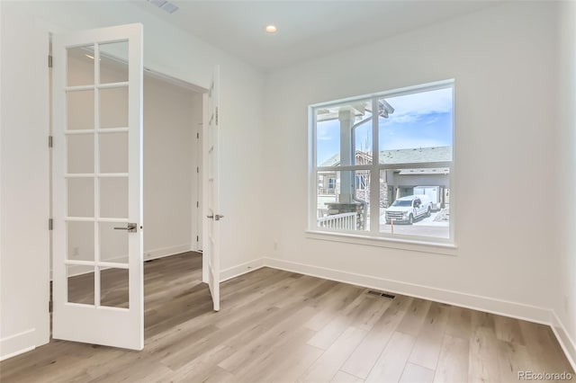 empty room with light wood-style flooring, baseboards, french doors, and recessed lighting