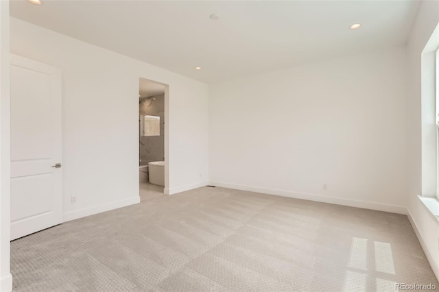 unfurnished bedroom with light carpet, recessed lighting, baseboards, and ensuite bathroom