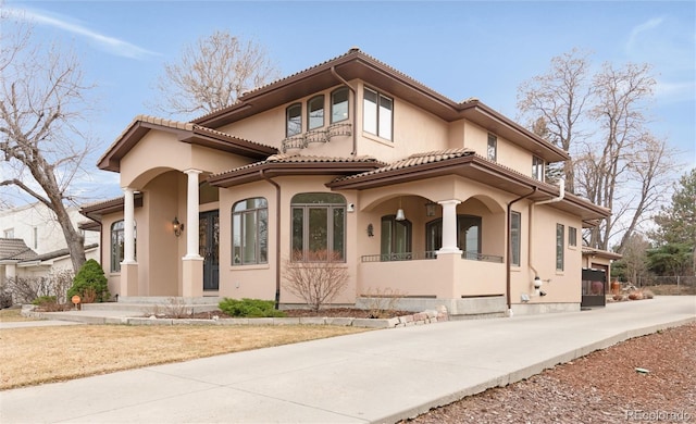 mediterranean / spanish home with stucco siding, a tiled roof, and driveway