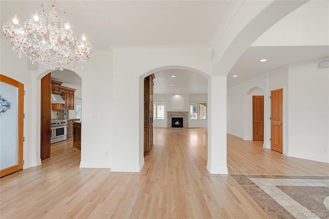 interior space with recessed lighting, light wood-style flooring, crown molding, and a lit fireplace