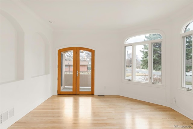 interior space featuring french doors, visible vents, light wood finished floors, and arched walkways