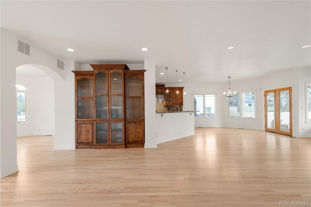 unfurnished living room with visible vents, a healthy amount of sunlight, and light wood-type flooring