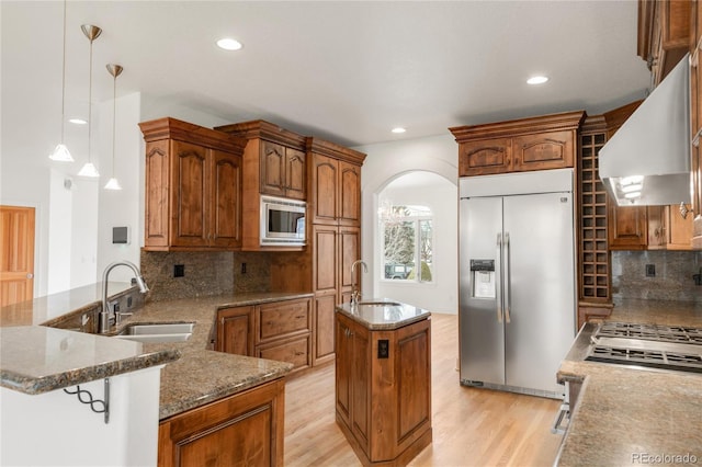 kitchen with a sink, built in appliances, arched walkways, and custom range hood