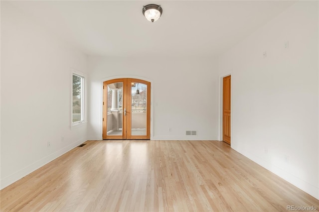 unfurnished room with visible vents, baseboards, light wood-type flooring, french doors, and arched walkways