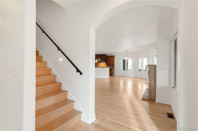 stairs with visible vents, recessed lighting, an inviting chandelier, and wood finished floors