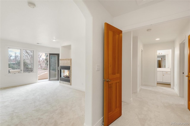 corridor featuring recessed lighting, baseboards, light carpet, and arched walkways